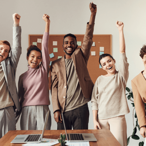 4 jeunes travailleurs qui lèvent le bras avec le sourire